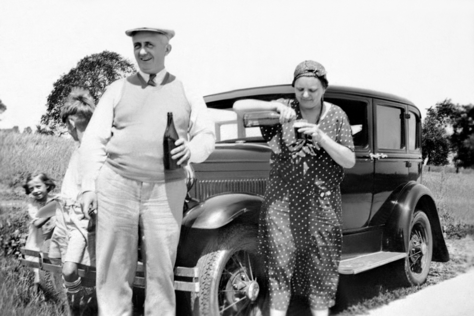 Eugene J. & Grace H. Smith McManus with son Joseph "William" and daughter Mary Ann peering around automobile